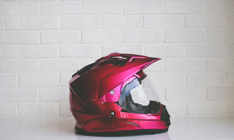 Red Metallic Motorcycle Helmet against White Brick Wall