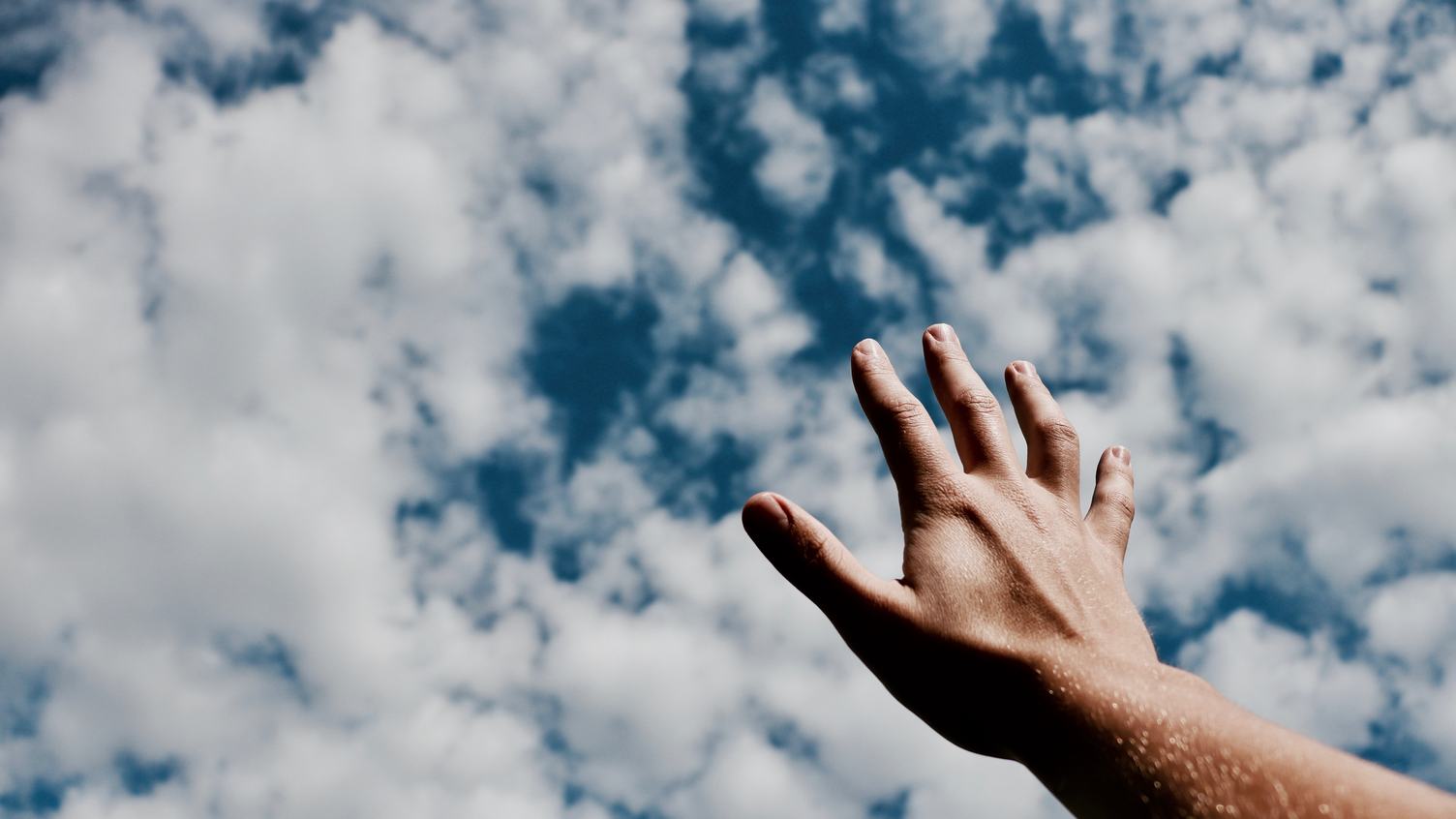 Free Photo Human Hand Against Blue Sky With Clouds