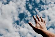 Human Hand against Blue Sky with Clouds