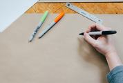 Female Hand with a Marker Writing on Clean Brown Wrapping Paper