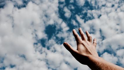 Human Hand against Blue Sky with Clouds