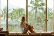 Young Blond Woman Sitting on a Window Looking Outside