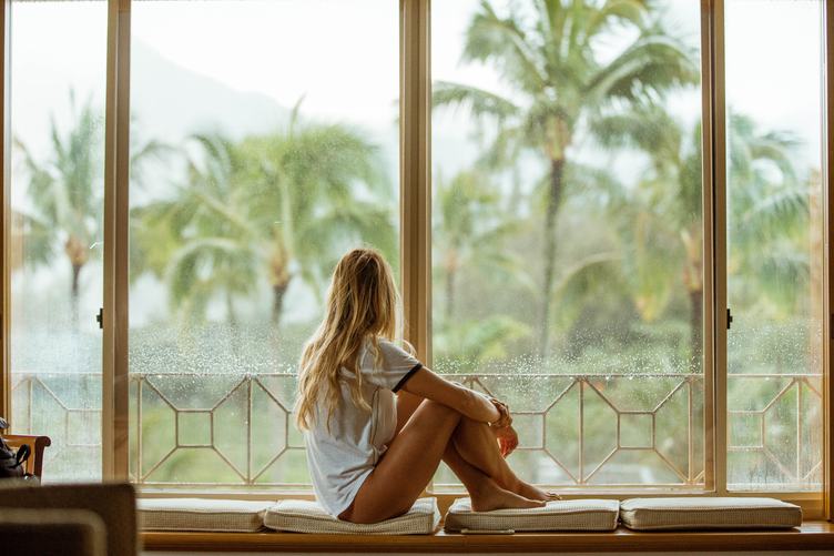 Young Blond Woman Sitting on a Window Looking Outside