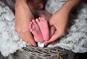 Mother Hands Holding Feet of Newborn Baby
