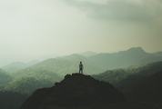 Man Standing on Top of a Mountain and Enjoying View
