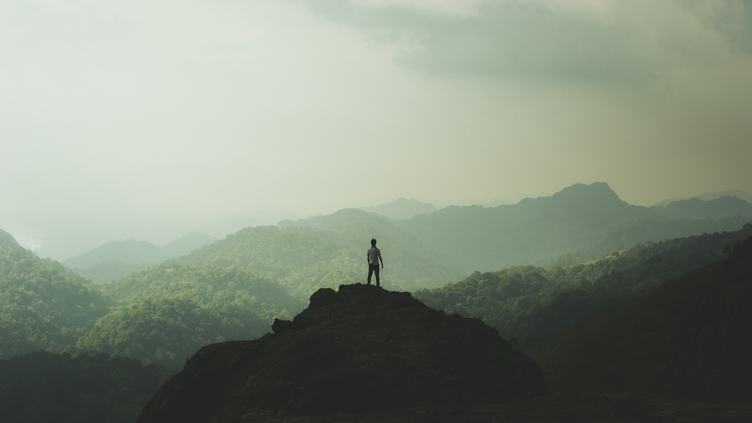 Man Standing on Top of a Mountain and Enjoying View