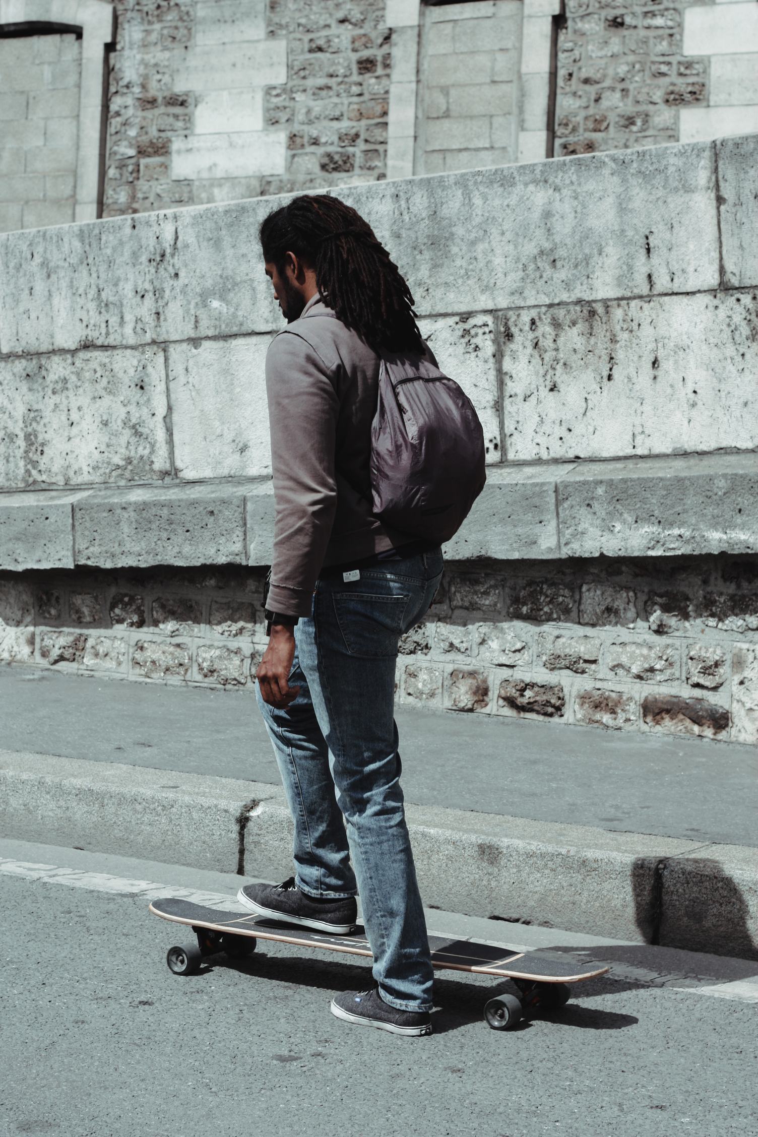 Young Black Man with Dreadlocks Getting on his Skateboard