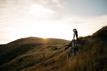 Young Couple Kissing on the Rock at Sunset