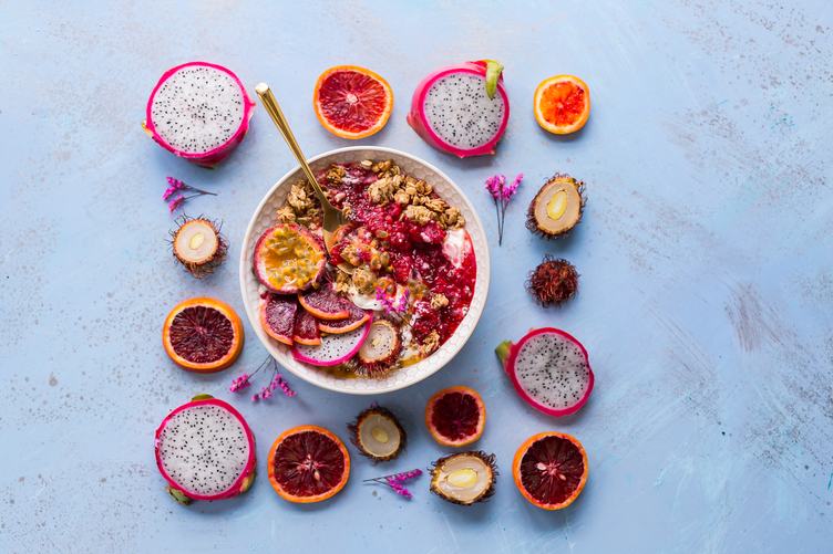 A Bowl of Healthy Breakfast Muesli with Fruits Pitaya, Blood Orange and Rambutan