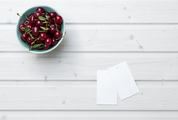 Empty Tag Cards and Cherries in Bowl on White Wooden Background