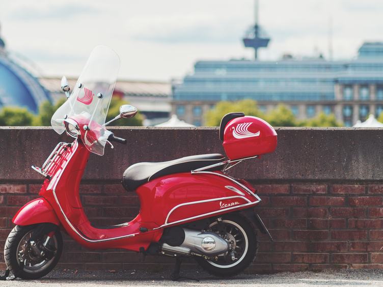 Red Vespa Scooter Parked by the Small Brick Wall