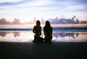 Two Young Woman Sitting on the Beach during Sunset