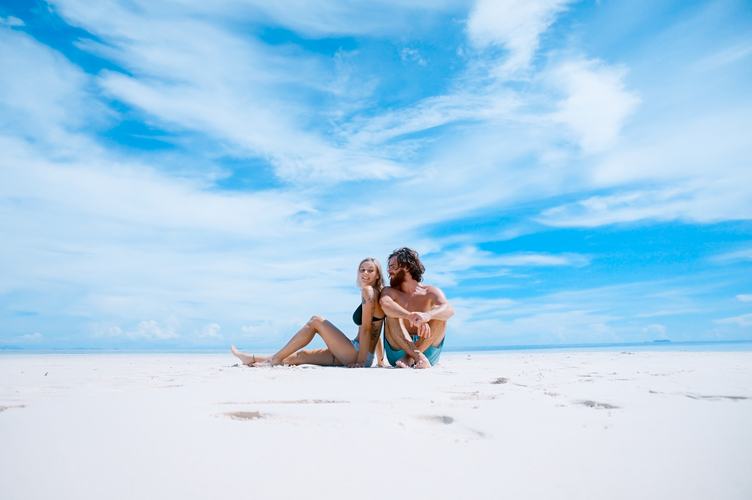 Couple Sitting on the Beach against Blue Sky