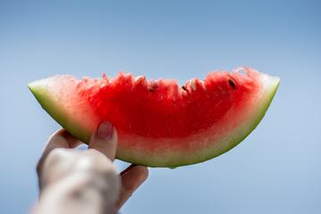 Woman Holding Juicy Slice of Watermelon in Her Hand