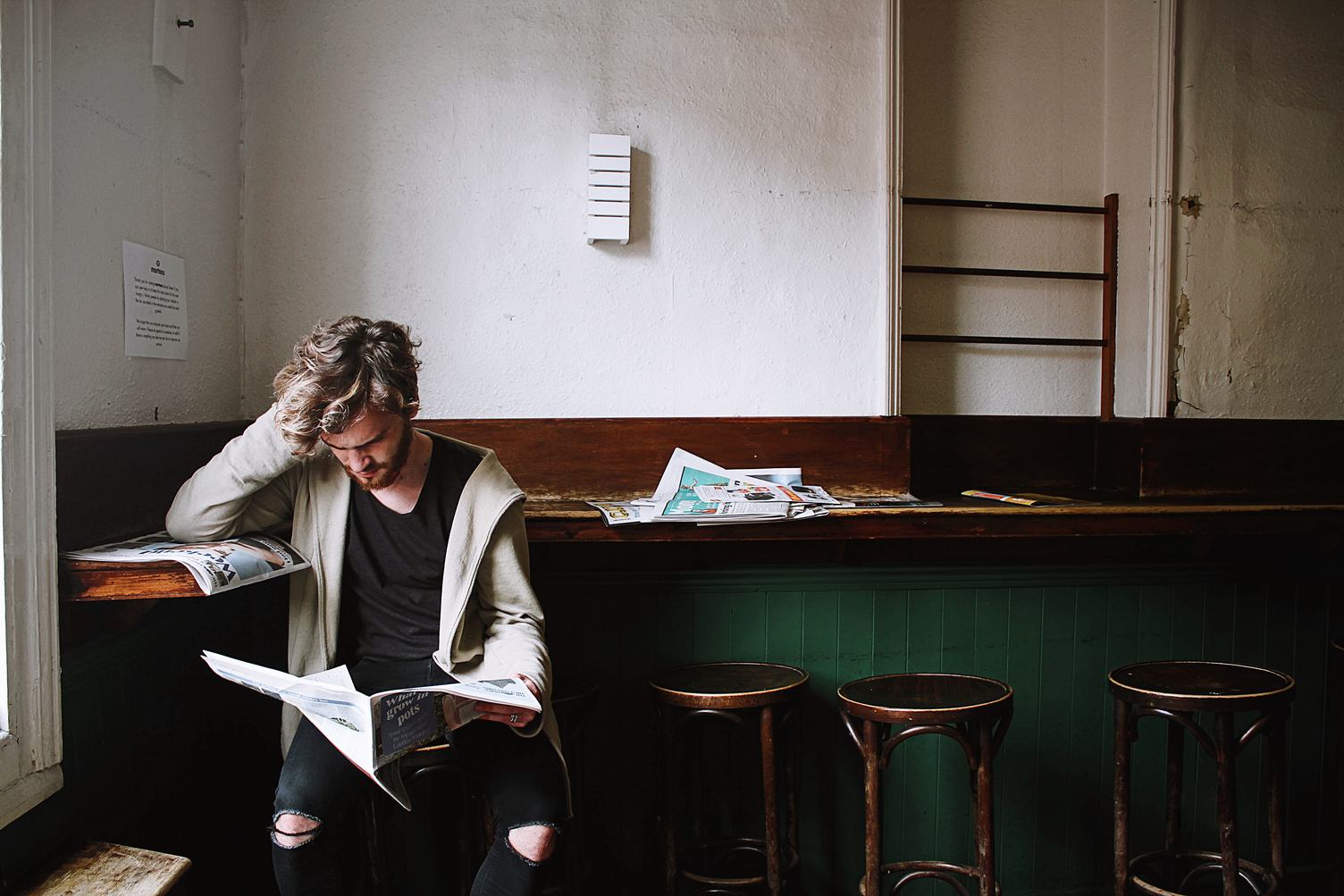 Young Bearded Man Reading a Newspaper in a Cafe