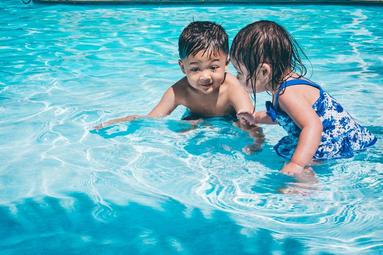 Little Girl and Boy Play in the Swimming Pool