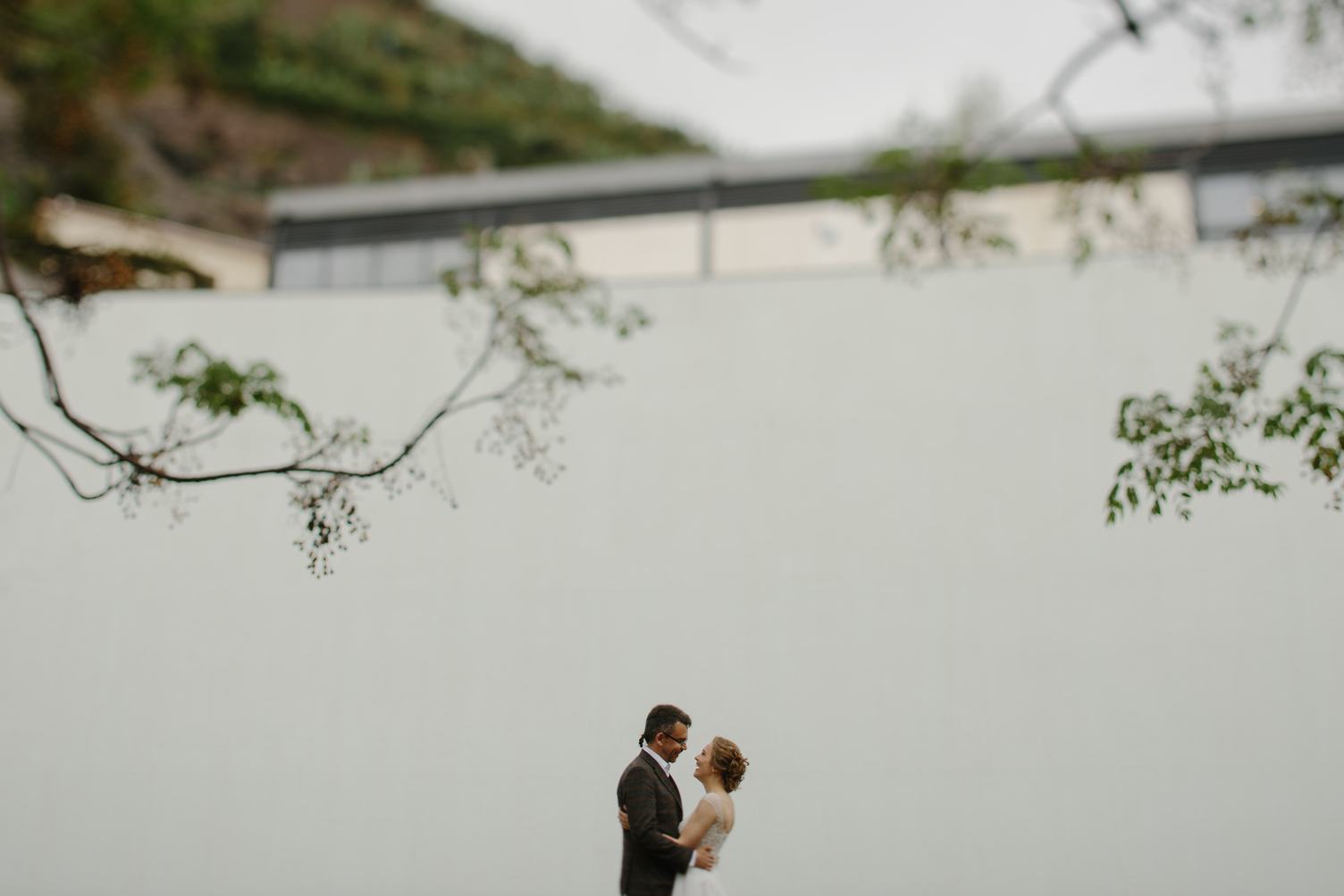 Bride and Groom Standing at a High White Wall