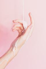 Liquid Draining the Woman's Hand on a Pink Background