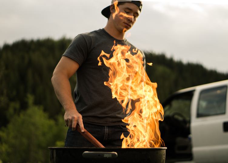 Young Man Burns the Grill Outdoors