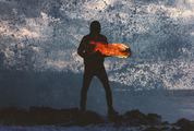 Mysterious Person Holding Fire Torch against Splashing Waves