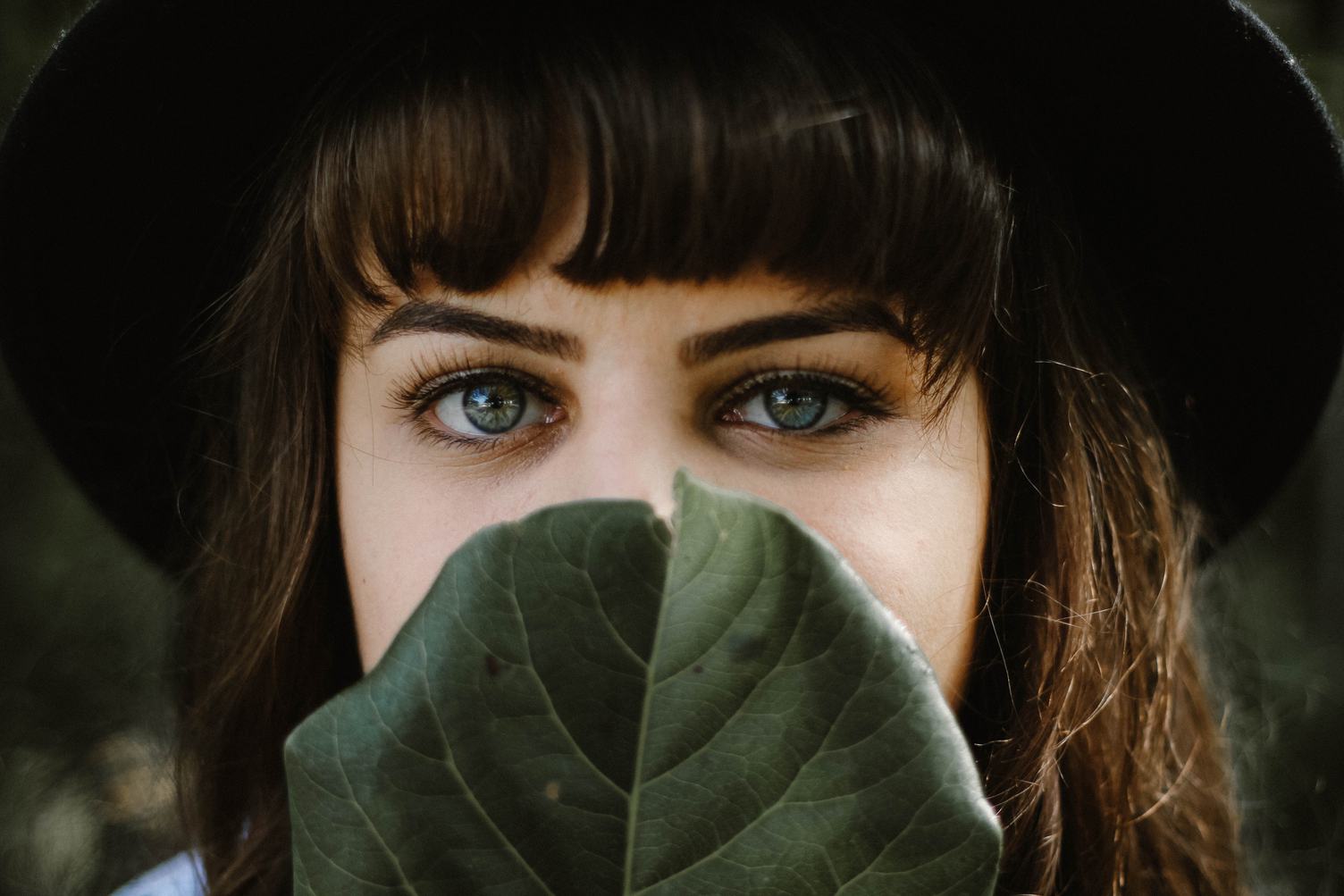 Lovely Brunette Covers Her Mouth behind the Leaf