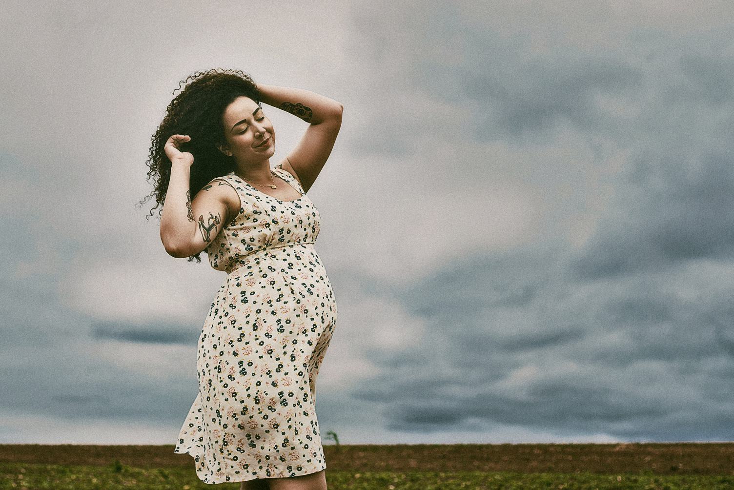 Pregnant Woman with Curly Hair Walking on Field