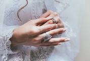 Hands of the Bride against White Wedding Dress