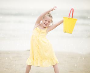 Girl in Yellow Dress Having Fun Playing on a Beach with Bucket
