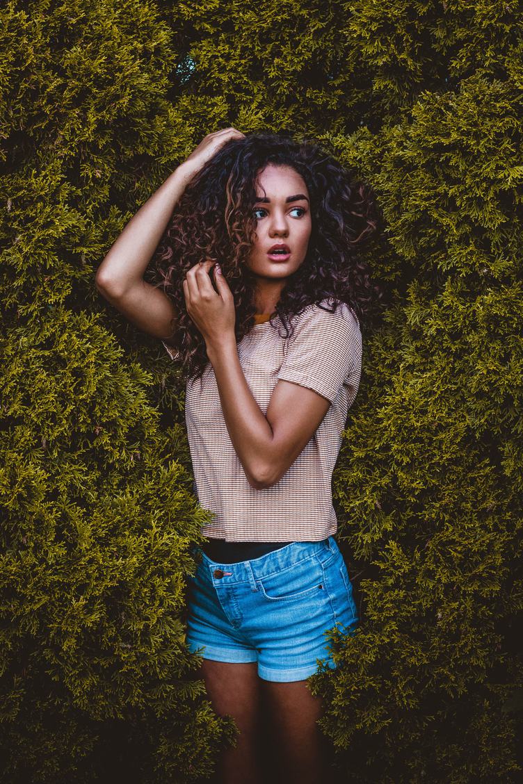 Portrait of Pretty Woman with Long Curly Hair Outdoors