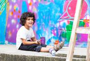 Young Boy Sitting against a Colorful Graffiti Wall