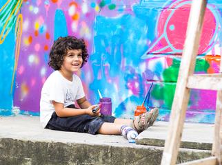 Young Boy Sitting against a Colorful Graffiti Wall