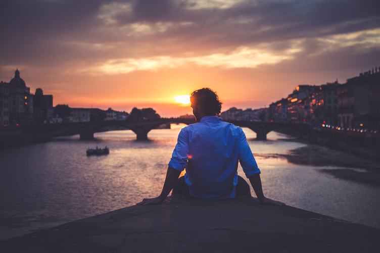 Man Enjoying View of Ponte Santa Trinita in Florence at Sunset