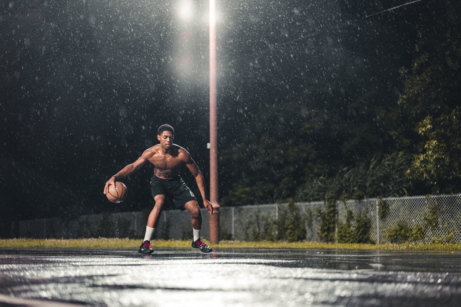 Athlete Male Playing Basketball at Rainy Night Outdoors
