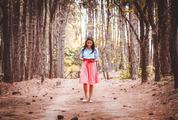 Cute Brunette Walking and Reading Book in the Forest