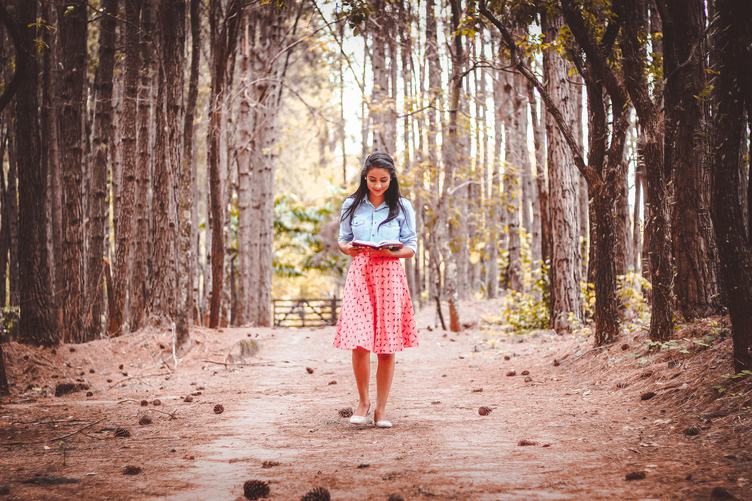 Cute Brunette Walking and Reading Book in the Forest