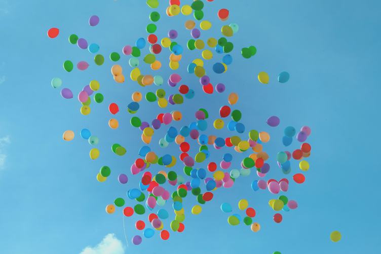 Multicolored Balloons Floating up into a Blue Sky