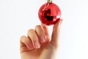 Hand Holding Red Christmas Ball on a White Background