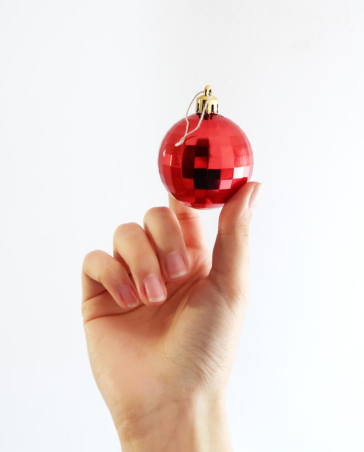 Hand Holding Red Christmas Ball on a White Background