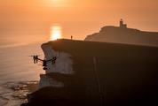 The Person Controls the Dron on the Cliff during the Sunset