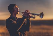 Young Man with Black Hat Playing a Trumpet at Sunset