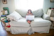 Little Girl Sitting on a Couch with MacBook on Her Lap