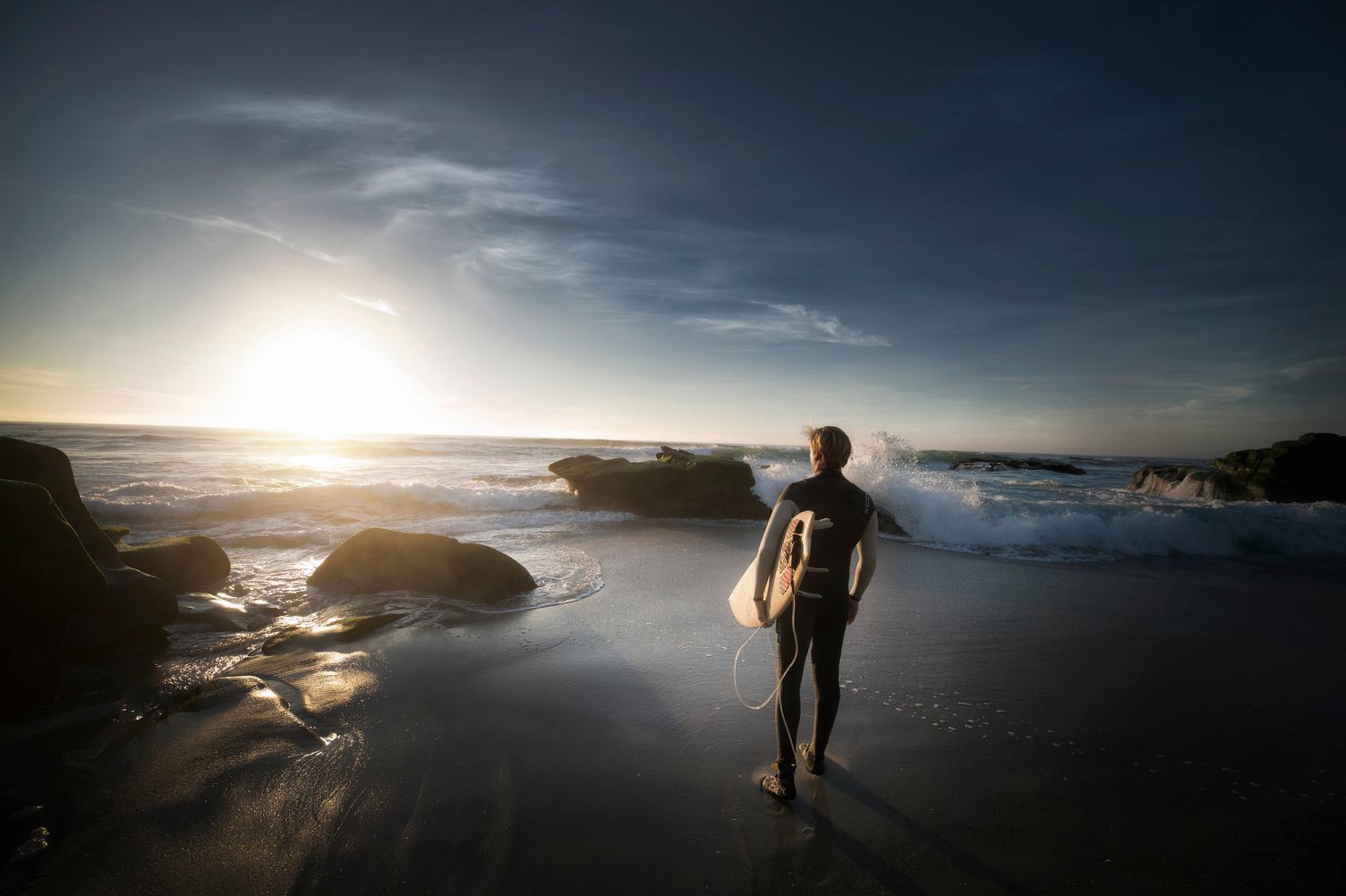 Surfer Walking on the Beach at Sunset