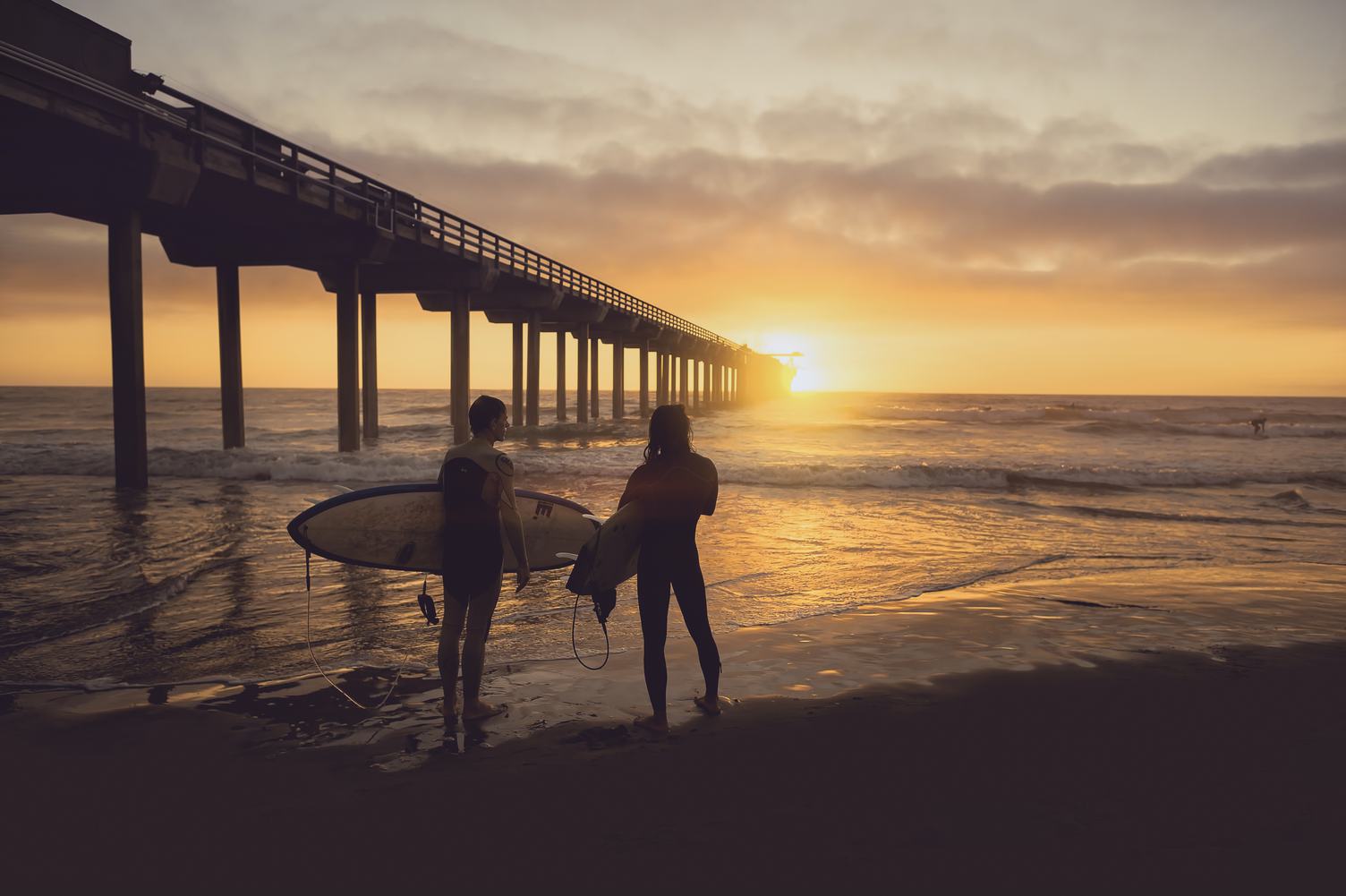 Silhouette of Two Surfers Carrying Their Surfboards on Sunset