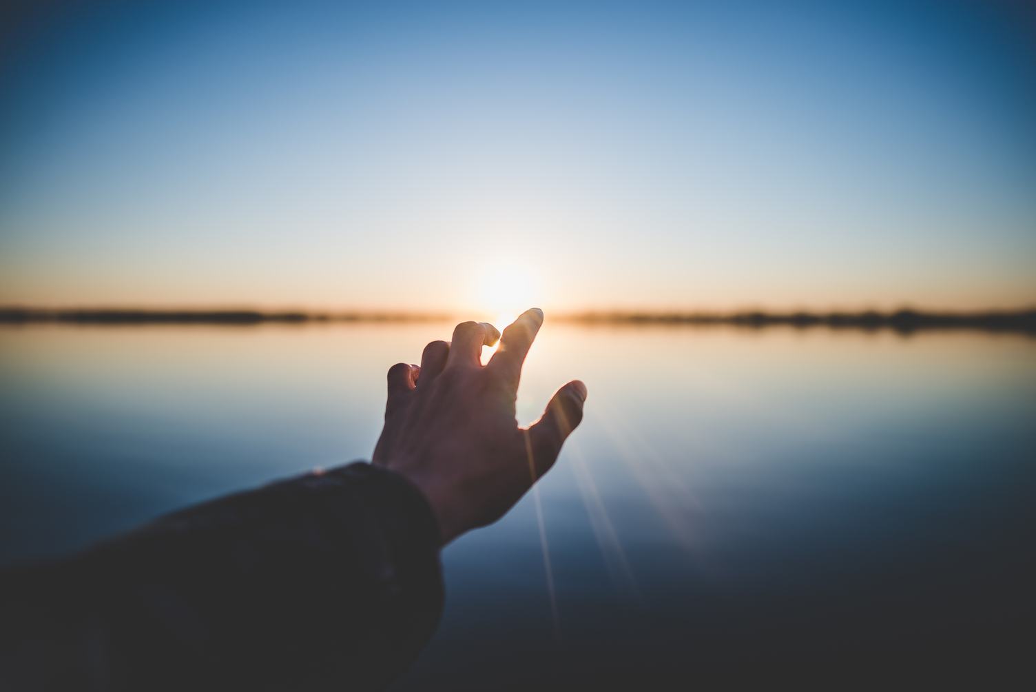 Hand Touching the Sun on the Horizon