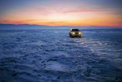 Car on an Frozen Lake Baikal at Sunset