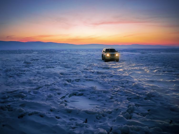 Car on an Frozen Lake Baikal at Sunset