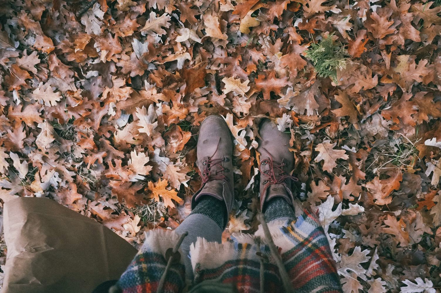 Legs in Leather Boots Standing on a Ground with Autumn Leaves