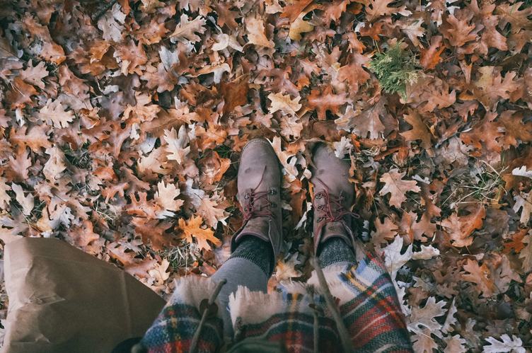 Legs in Leather Boots Standing on a Ground with Autumn Leaves
