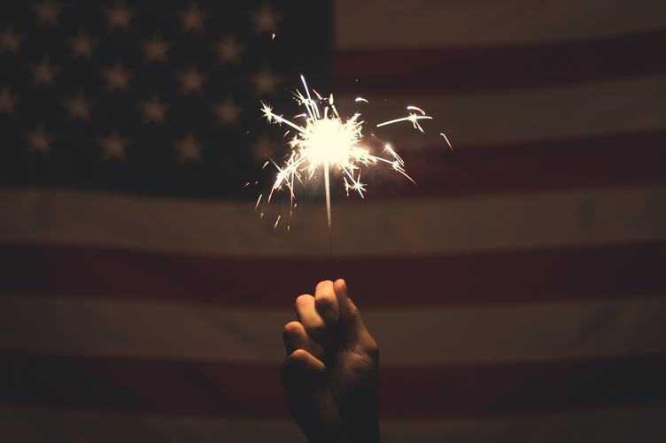 Fireworks in Hand, USA Flag on Background