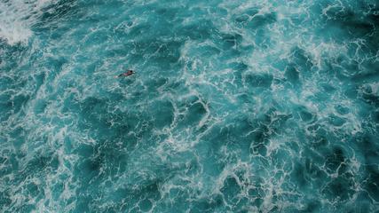 Aerial View of a Man on a Surfboard in the Turquoise Ocean